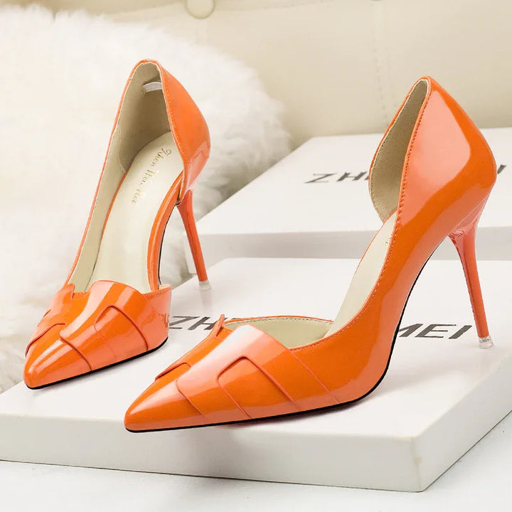 Bright orange patent leather high heel pumps with pointed toes on white box background