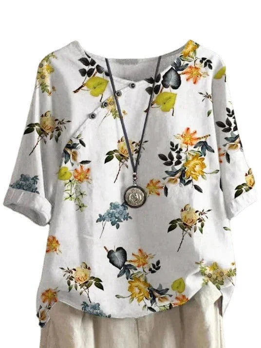 White floral print casual blouse with rolled sleeves and button details, accessorized with a pendant necklace