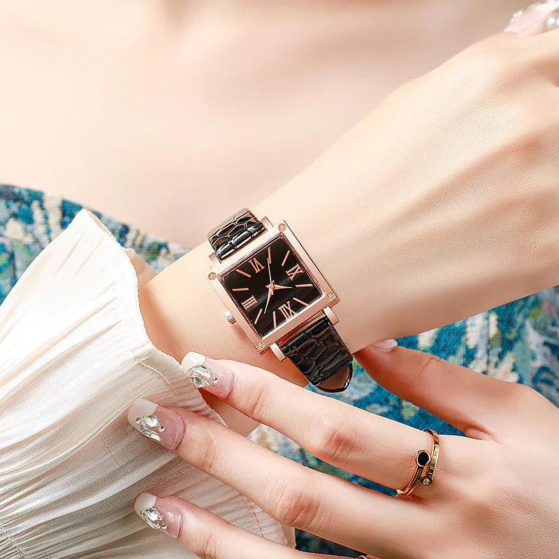 Elegant wristwatch with black square dial and leather strap on woman's wrist with decorated nails
