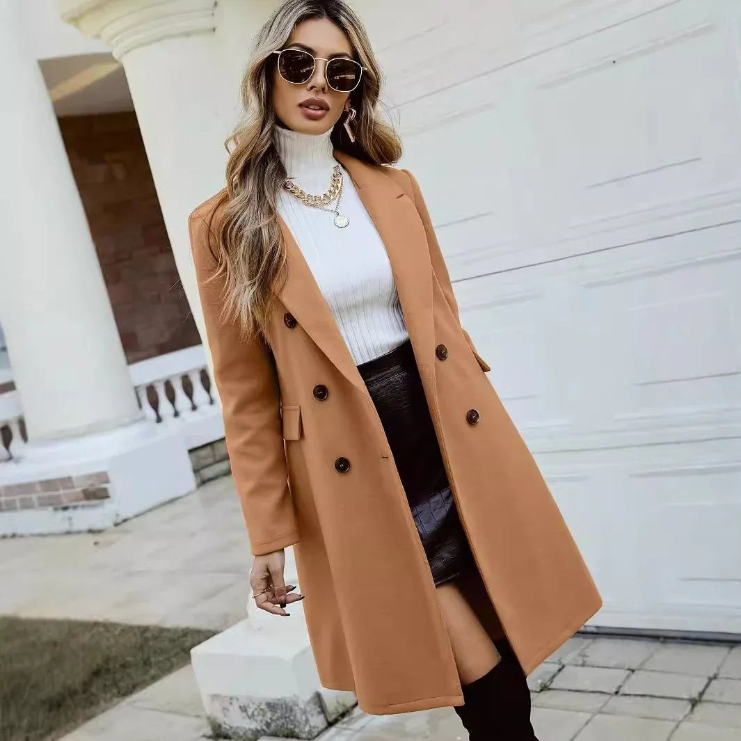 Woman wearing camel coat, white turtleneck sweater, black skirt, knee-high boots, and sunglasses outdoors