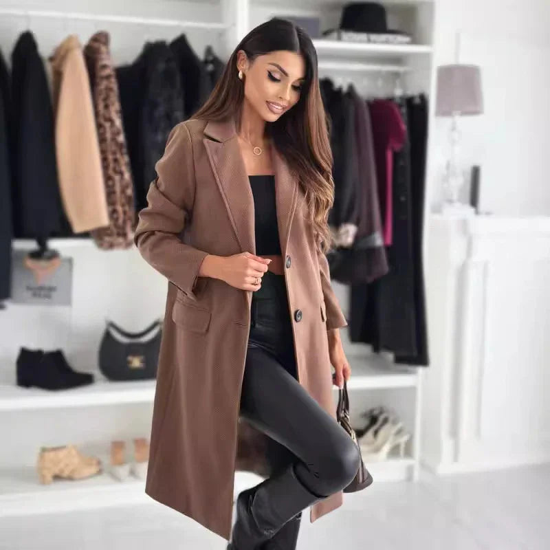 Fashionable woman in brown long coat, black crop top and leather pants posing in stylish closet