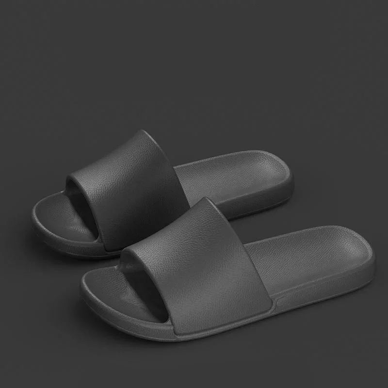 pair of black slide sandals with textured straps and cushioned soles on dark background