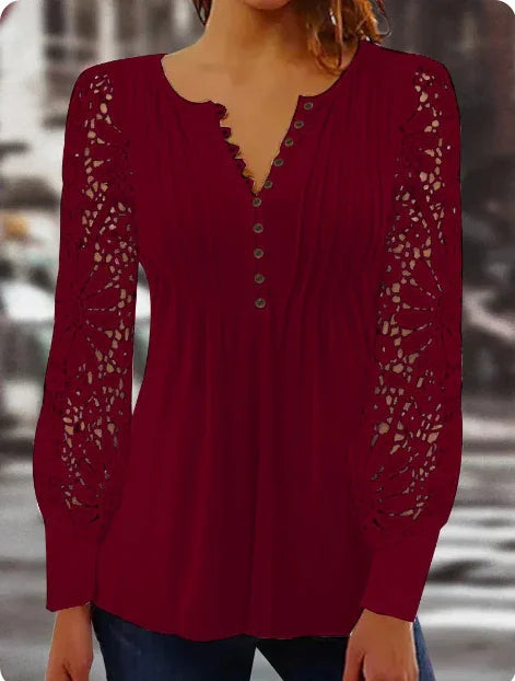 Woman wearing a burgundy long-sleeve top with floral lace sleeves and buttoned front