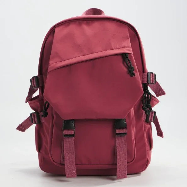 Red backpack with front zip pocket, adjustable straps, and side buckles on white background