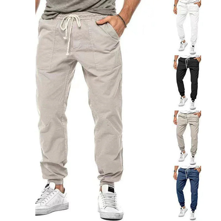 Men's casual jogger pants with drawstring waist in beige, white, black, and blue, paired with white sneakers
