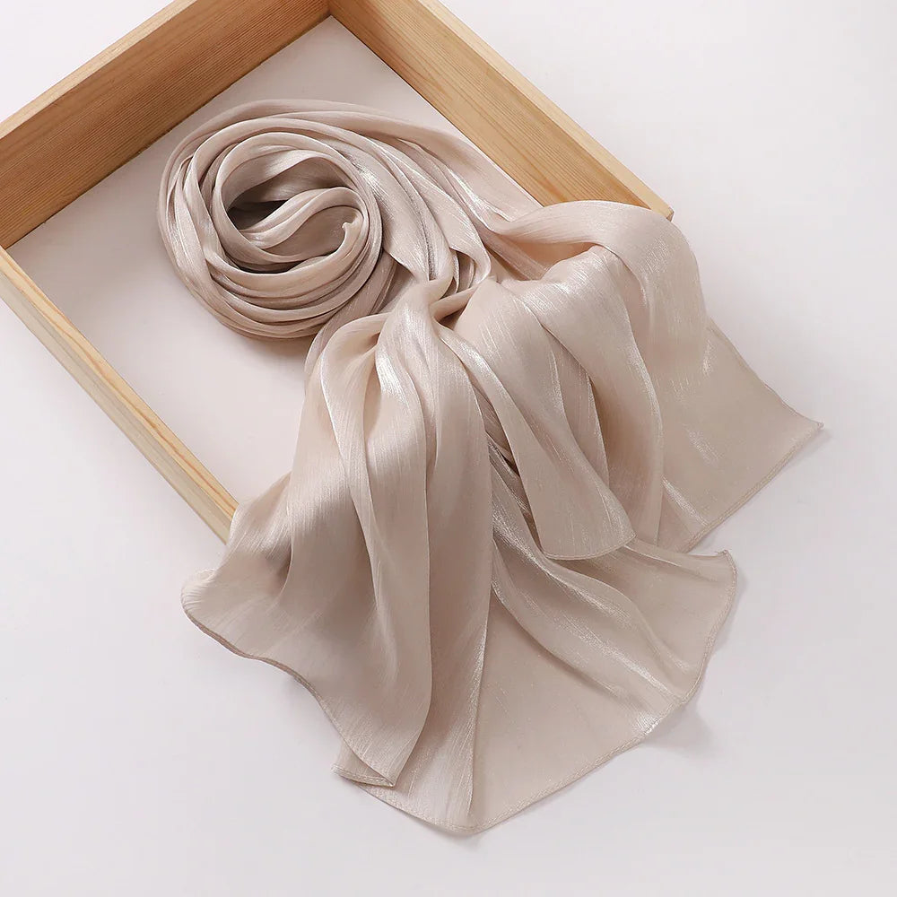 Soft beige shiny silk scarf displayed on a wooden frame against a white background