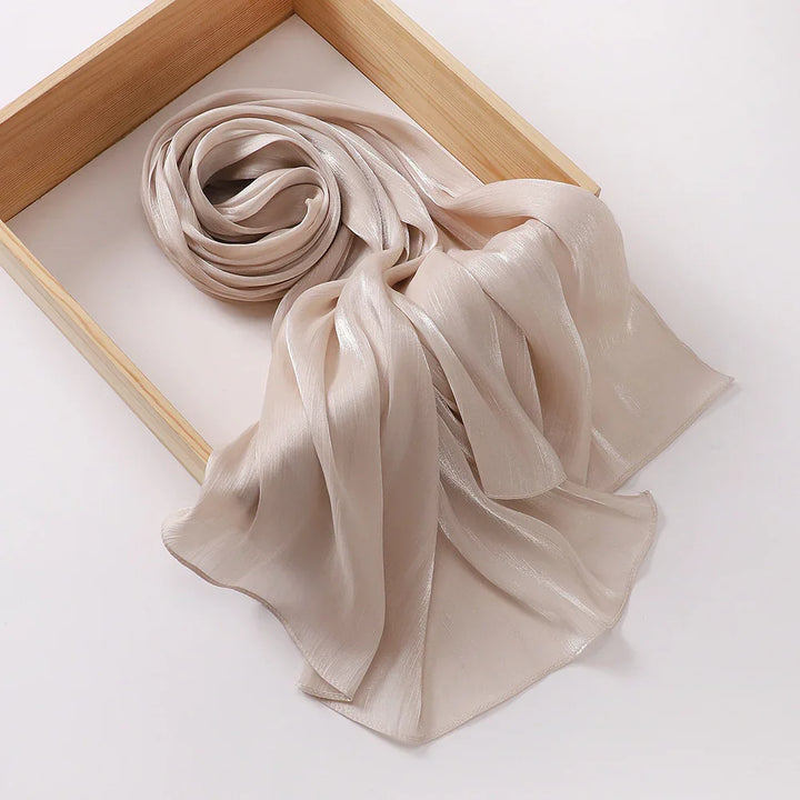 Soft beige shiny silk scarf displayed on a wooden frame against a white background