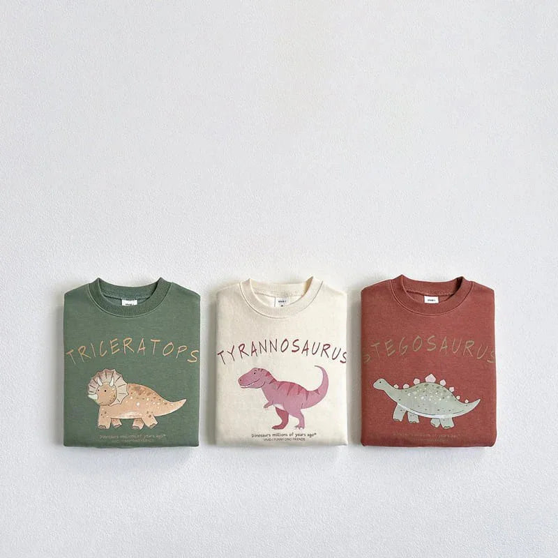 Folded green, white, and brown dinosaur-themed sweatshirts with Triceratops, Tyrannosaurus, and Stegosaurus prints