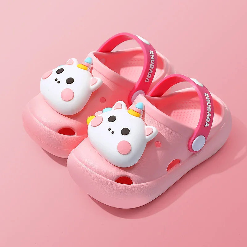 Pink kids clogs with unicorn face charms and adjustable heel straps on pink background