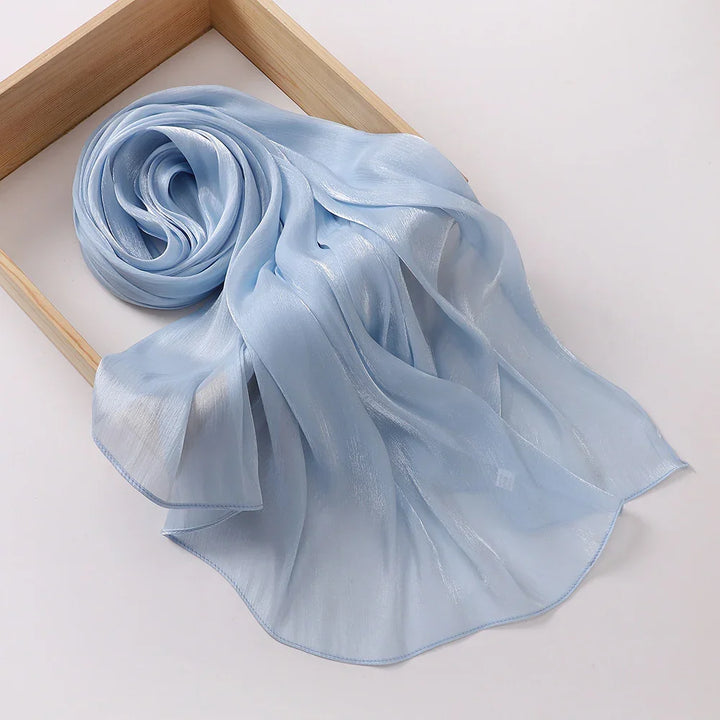 Light blue sheer chiffon scarf with soft shimmer displayed on wooden frame against white background