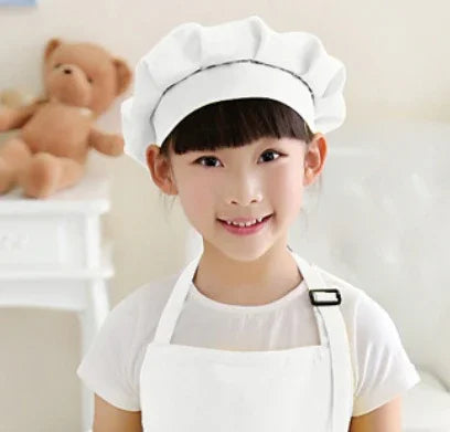 Smiling young girl wearing a white chef hat and apron in a bright kitchen setting