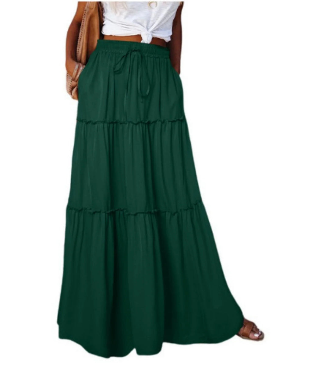 Woman wearing a dark green tiered maxi skirt with elastic waistband and drawstring, paired with a white knotted top