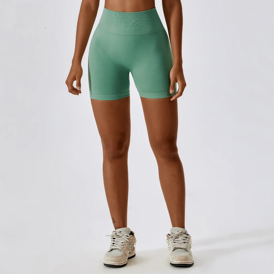 Woman wearing high waisted green seamless biker shorts and white sneakers