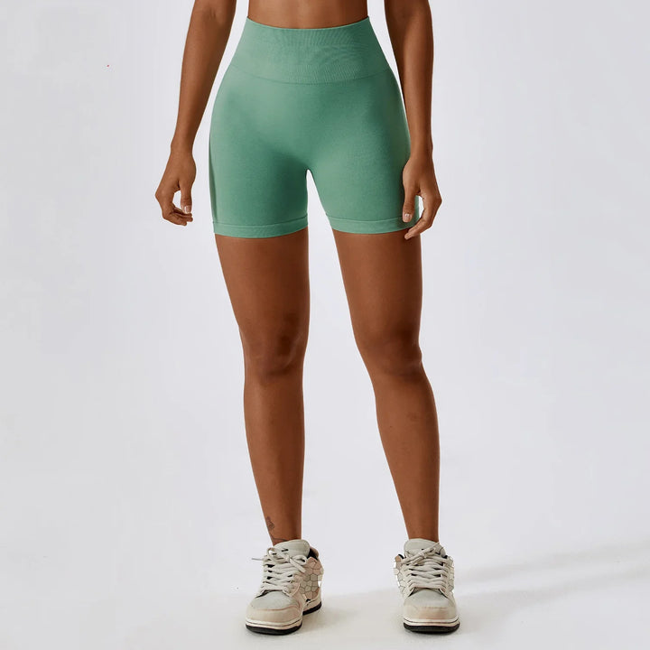 Woman wearing high waisted green seamless biker shorts and white sneakers