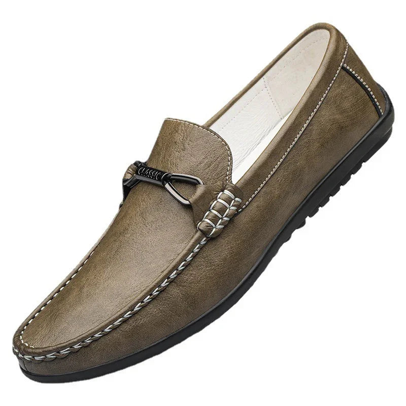 Men's brown leather slip-on loafer with black rubber sole and decorative metal buckle