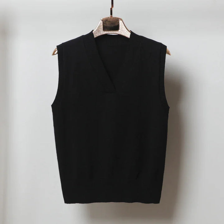 Black sleeveless V-neck knitted sweater vest on wooden hanger against plain wall