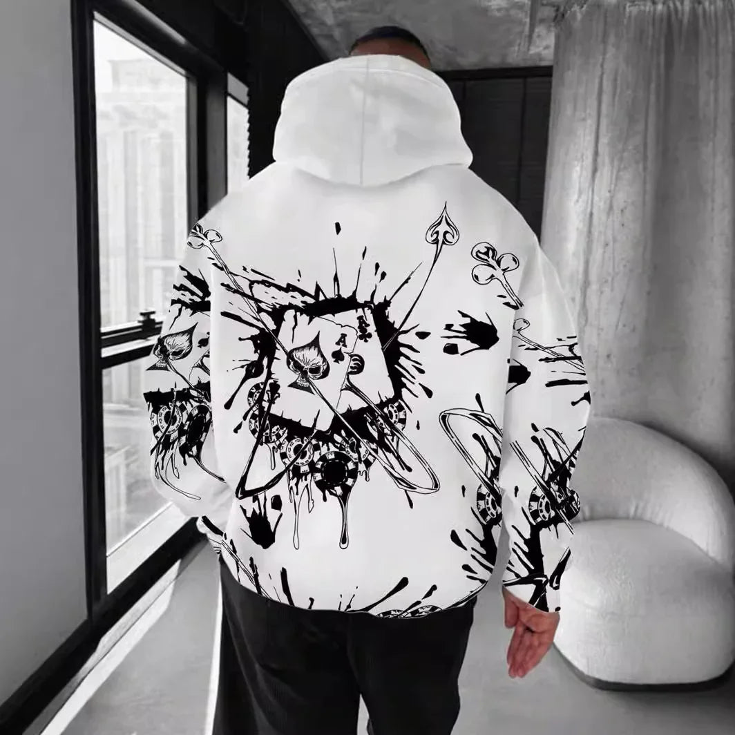 Man wearing white hoodie with black abstract splatter and playing cards design indoors