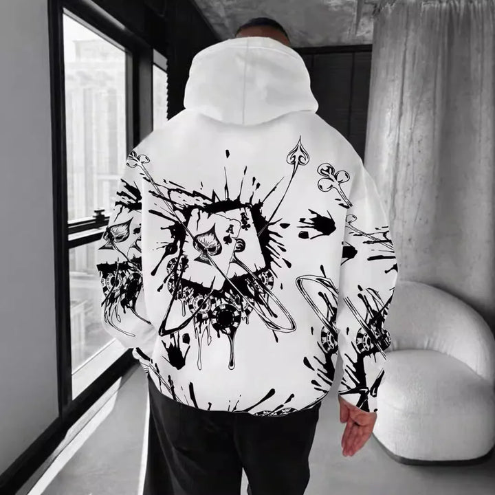 Man wearing white hoodie with black abstract splatter and playing cards design indoors