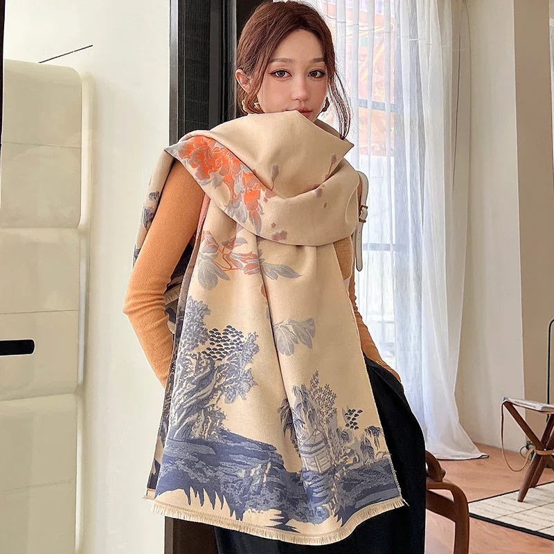 Woman wearing a large beige scarf with blue and orange floral and landscape print indoors