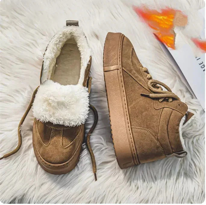 pair of brown suede winter shoes with white fluffy lining and thick soles on white fur surface