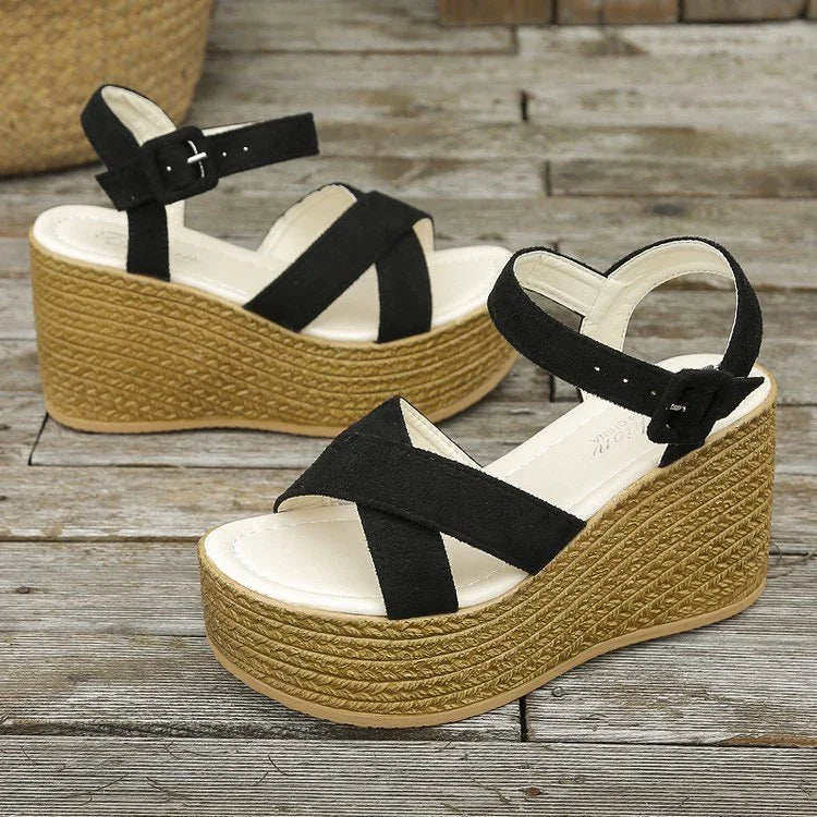 Black suede crisscross strap wedge sandals with braided jute platform heels on wooden floor