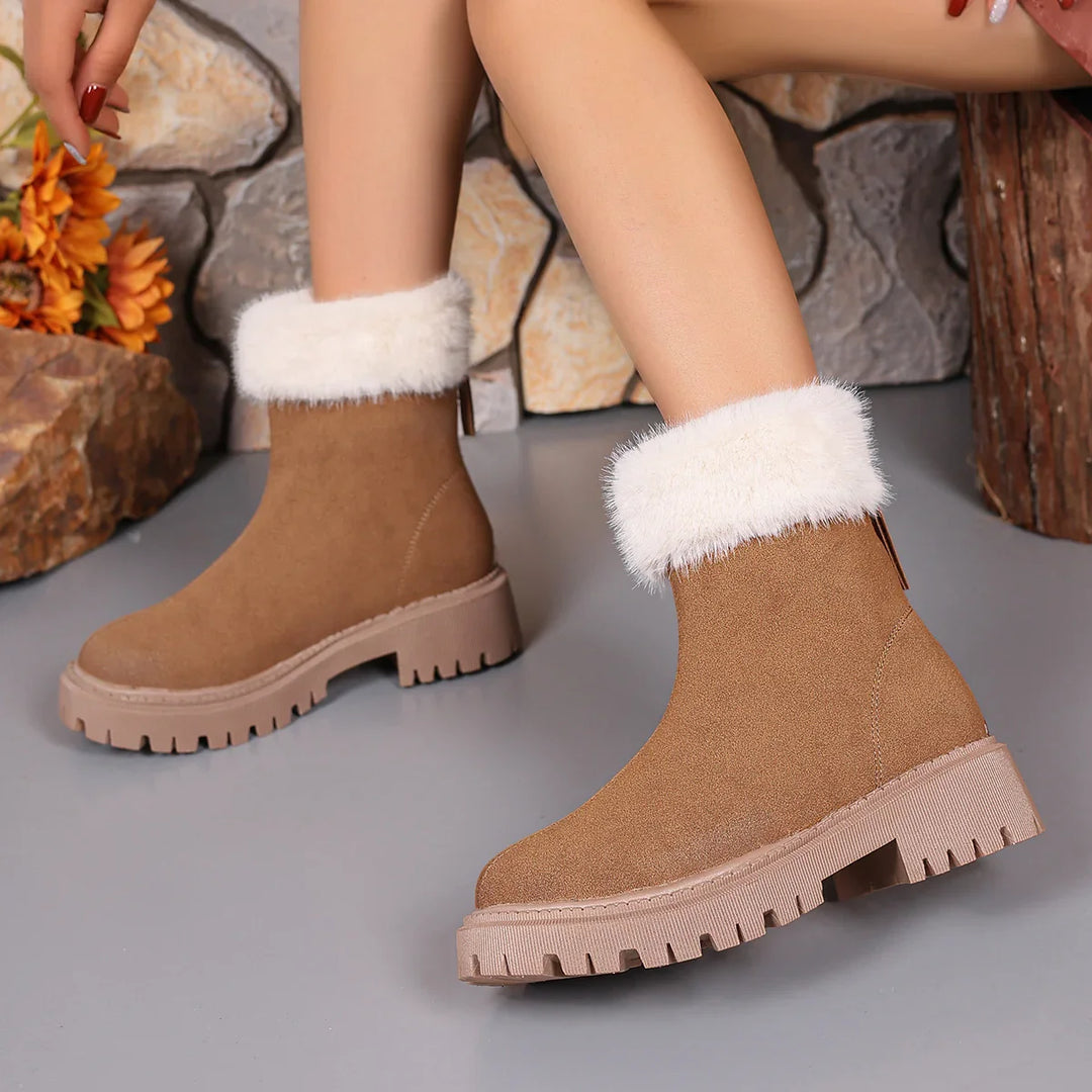 Women's brown suede ankle boots with white faux fur lining and rugged soles on grey floor