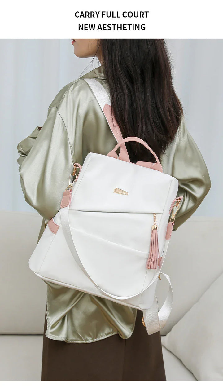 Woman wearing light green satin blouse carrying white and pink modern backpack with tassel