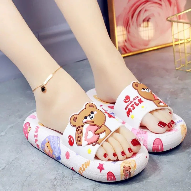 Feet wearing white slippers with cute teddy bear and chocolate milk designs on gray floor