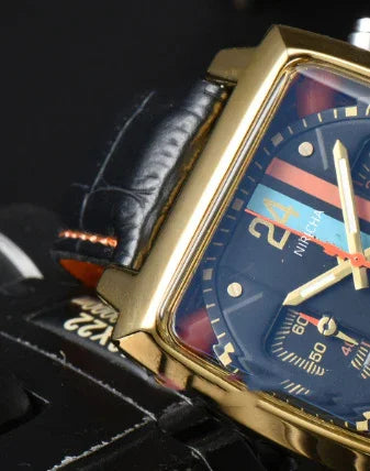 Close-up of a gold-framed wristwatch with black leather strap and blue dial showing 24-hour time markings