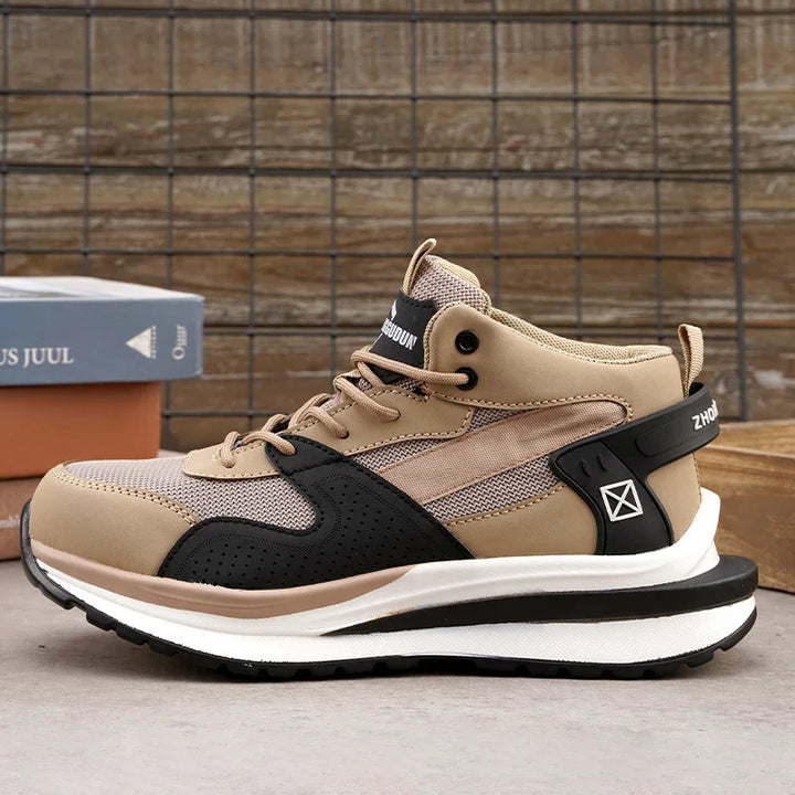 Beige and black high-top athletic sneaker with white sole on gray surface and wire grid background