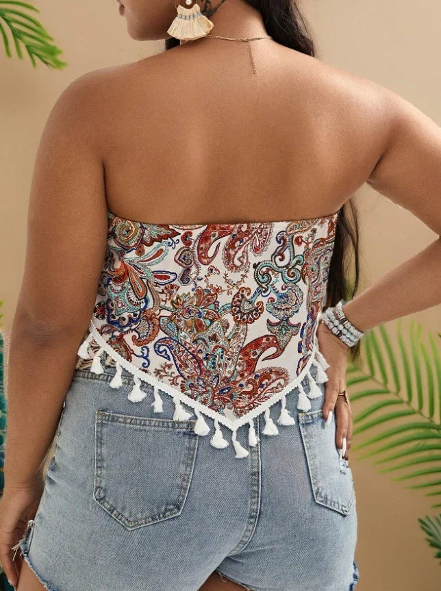 Woman wearing paisley print strapless top with white tassel trim and light blue denim shorts