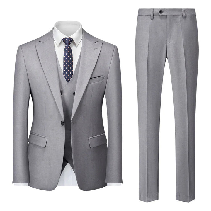 Gray men's three-piece suit with jacket, vest, pants, white shirt, and navy patterned tie