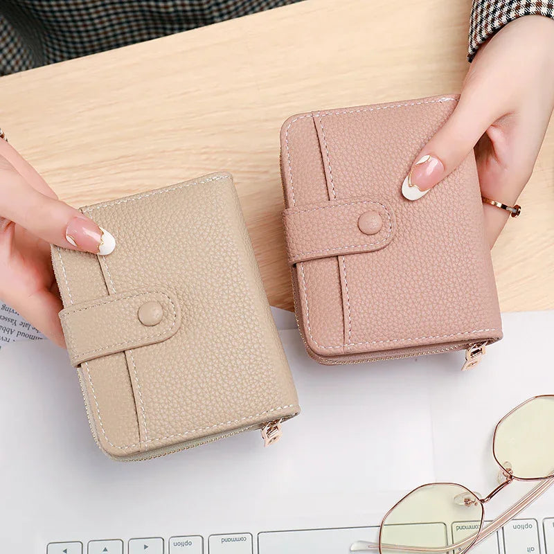 Two textured leather wallets in beige and dusty pink held by hands, with sunglasses and keyboard nearby