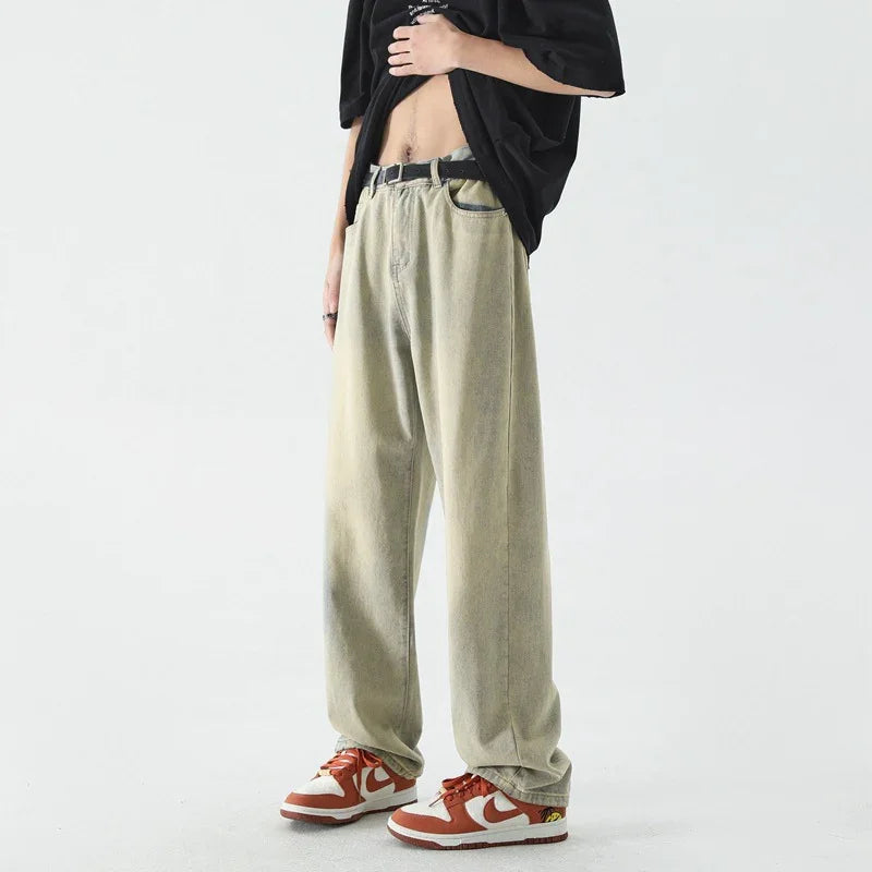 Man wearing beige baggy pants with black belt and red white sneakers on white background