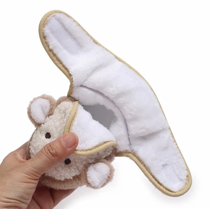 Hand holding a soft, plush bear-shaped face cleansing or makeup remover pad with a white microfiber interior