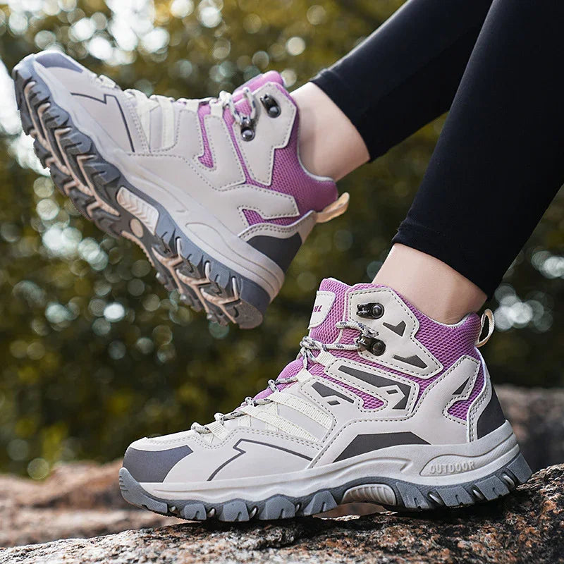 Light gray and purple outdoor hiking boots with rugged soles worn on black leggings outdoors