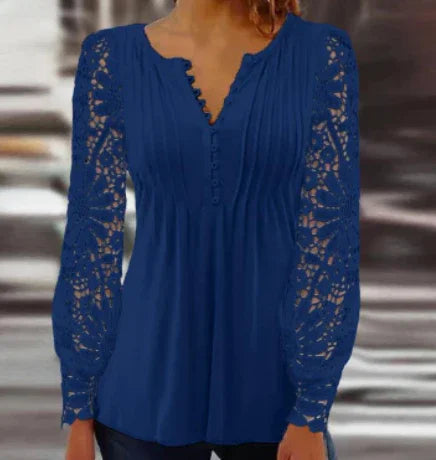 Woman wearing a navy blue blouse with lace long sleeves and button detail on the front