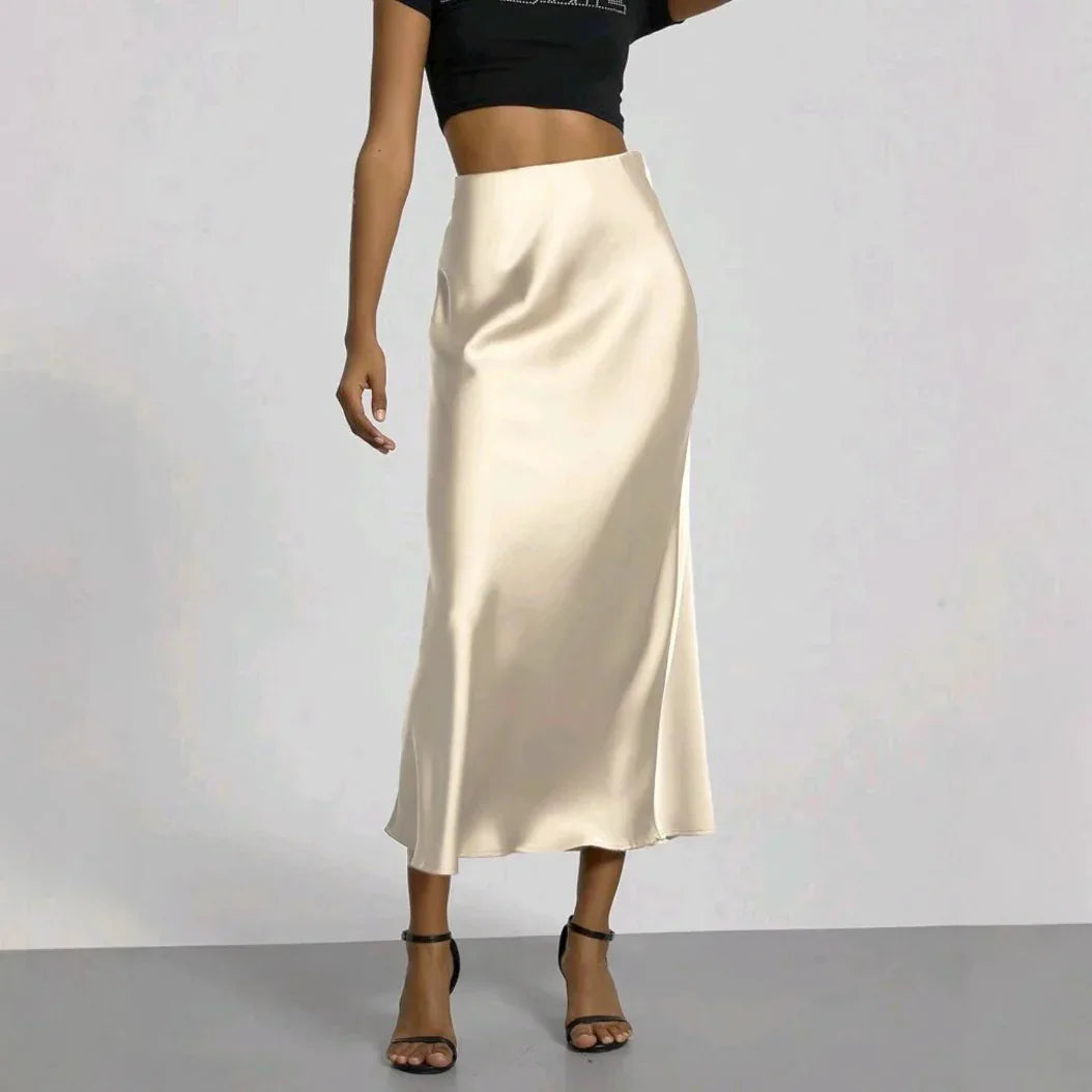 Woman wearing a cream satin midi skirt with black high-heeled sandals and a black cropped top