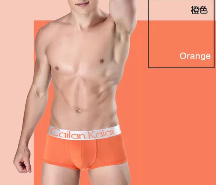 muscular male model wearing bright orange Cailan Kalai boxer briefs against matching orange background