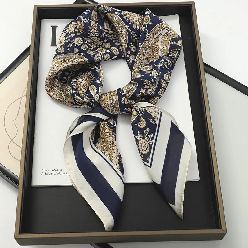Blue and beige paisley patterned silk scarf tied in a bow on black tray with book underneath