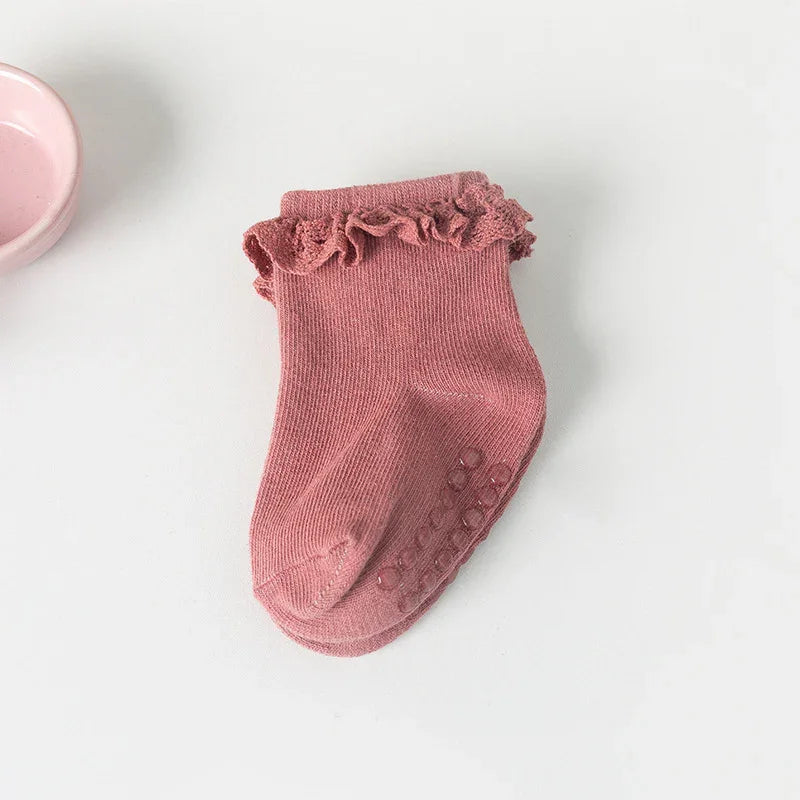Pink baby sock with ruffled cuff and non-slip grip dots on white background
