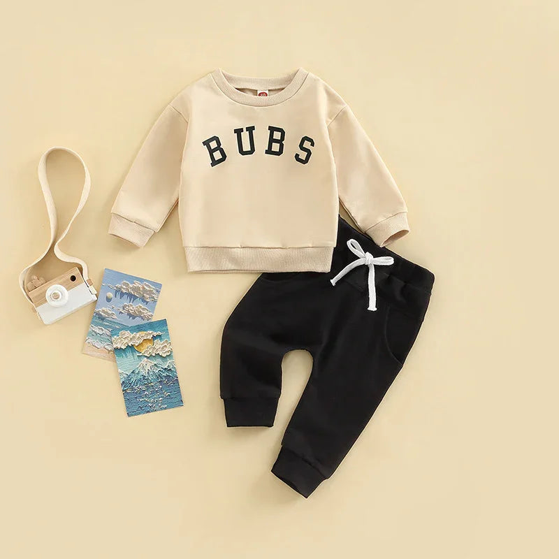 Beige toddler sweatshirt with BUBS text and black jogger pants with white drawstring on beige background