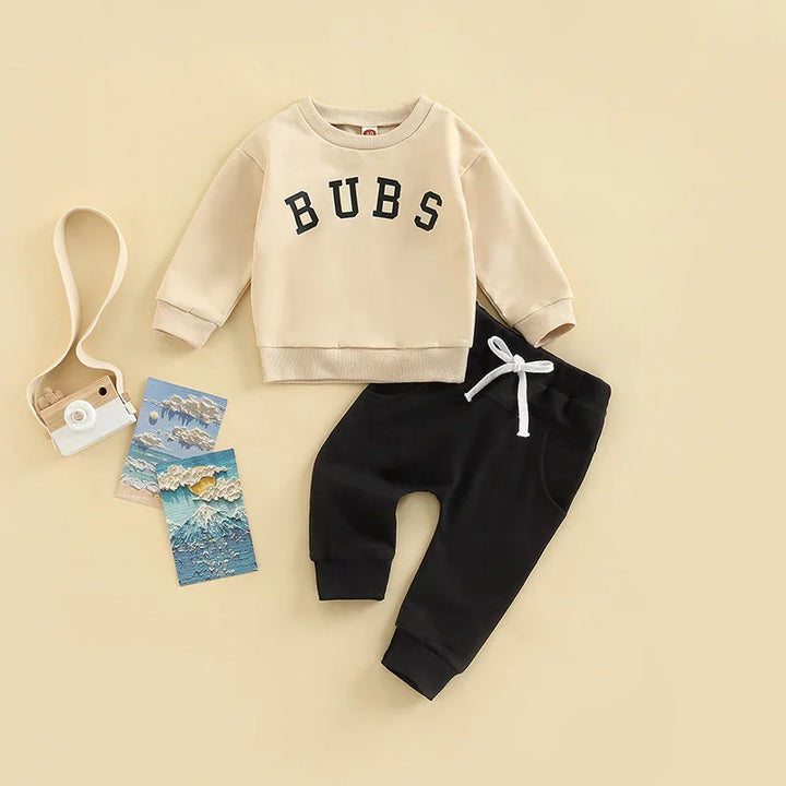 Beige toddler sweatshirt with BUBS text and black jogger pants with white drawstring on beige background