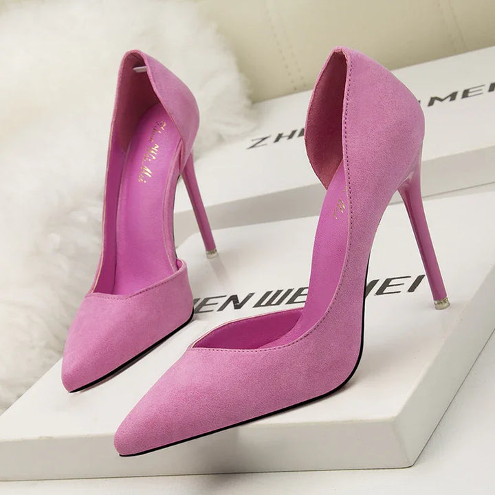 pair of pink suede high heel pumps with pointed toes on white box in bright light
