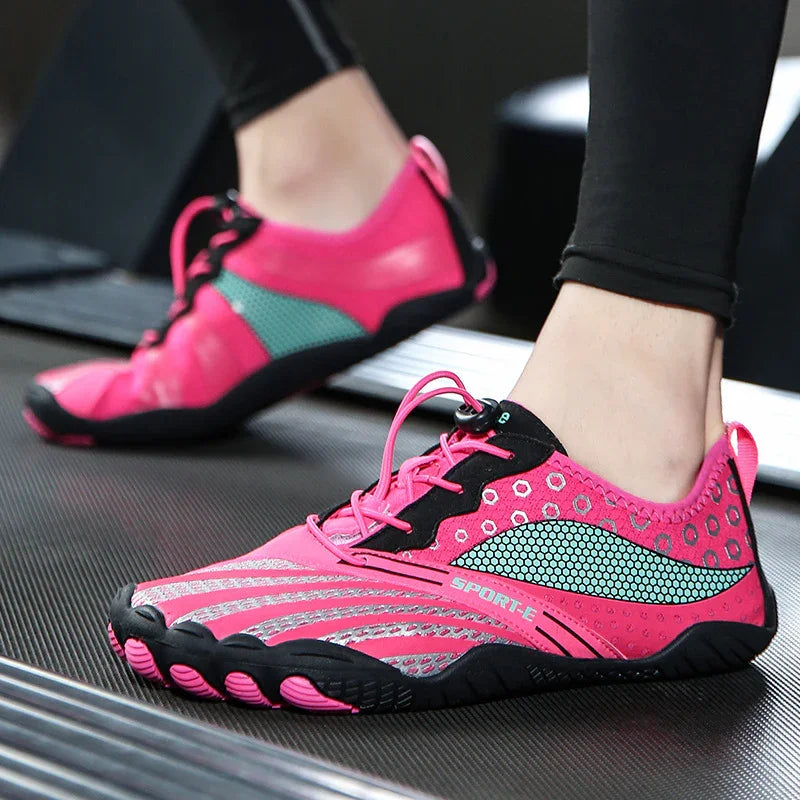 Close-up of pink and black lightweight barefoot running shoes with breathable mesh, worn on treadmill