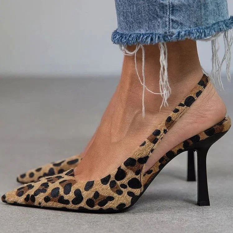 Close-up of feet wearing leopard print slingback high heels and distressed hem blue jeans on gray floor