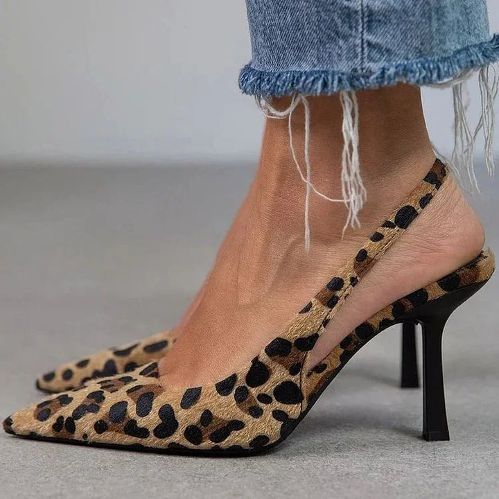 Close-up of feet wearing leopard print slingback high heels and distressed hem blue jeans on gray floor