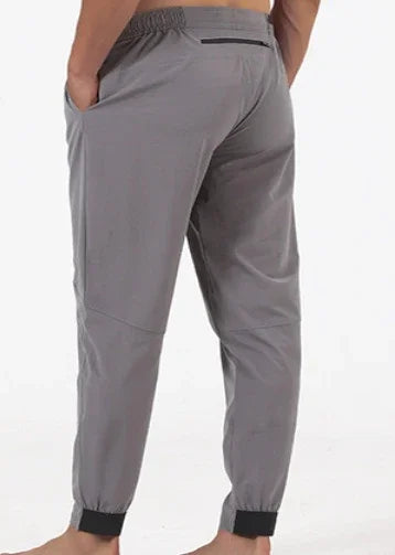 Rear view of person wearing light gray jogger pants with elastic ankle cuffs and side pockets
