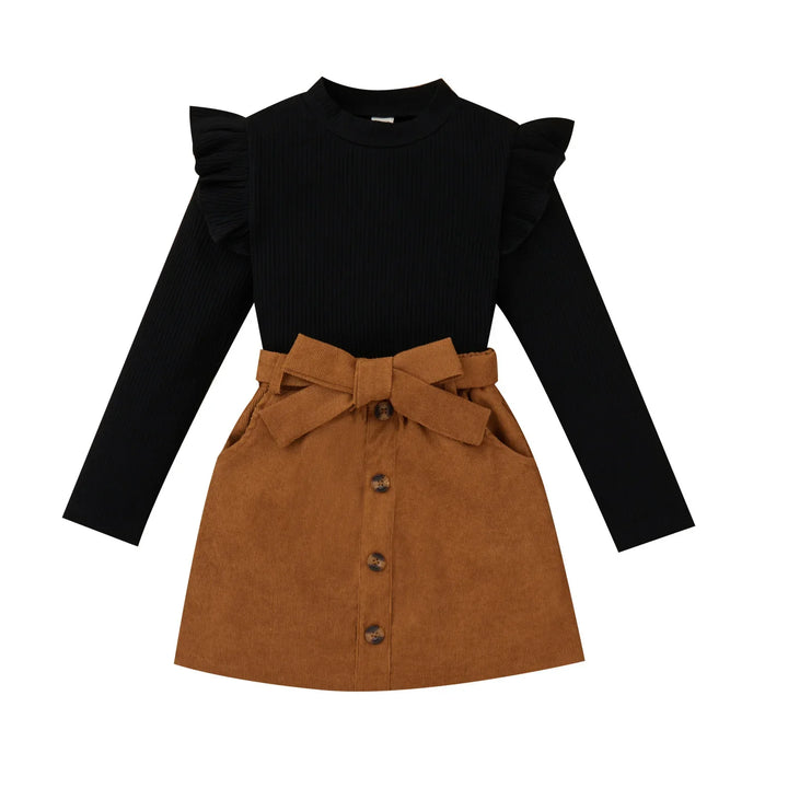 Black long sleeve top with ruffle shoulders and brown button-front skirt with bow belt