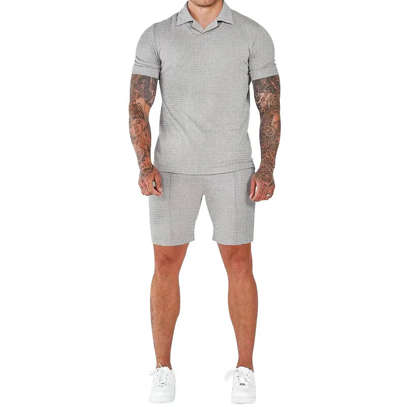 Man wearing light gray short-sleeve polo shirt and matching shorts with white sneakers